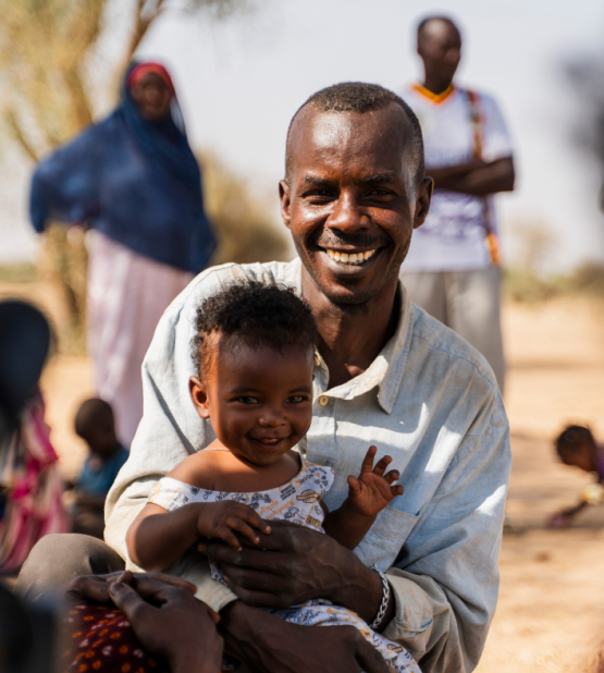 Mohamed holding his son and smiling