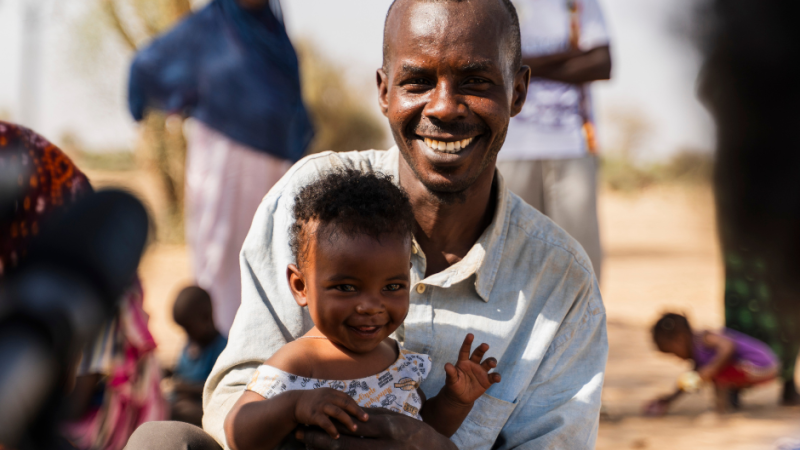 Mohamed holding his son and smiling